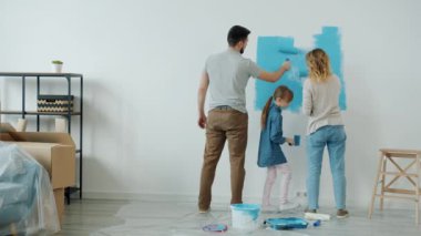 Anne-baba ve kızı duvar dekorasyonu odasını birlikte boyuyorlar.