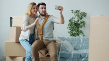 Kız ve erkek, taşınma sırasında akıllı telefon kullanarak yeni evi gösteren bir video konuşması yapıyorlar.