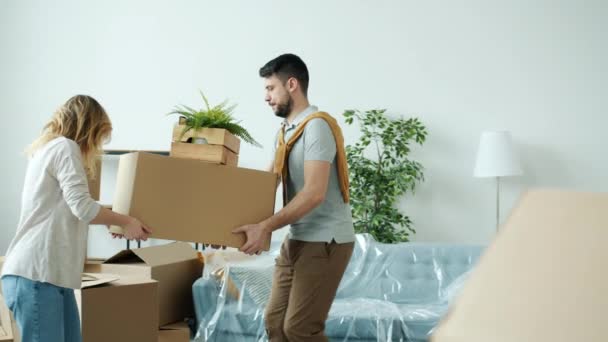 Movimiento lento de la chica y el chico que mueve cajas que llevan pertenencias que se trasladan a un nuevo apartamento — Vídeo de stock