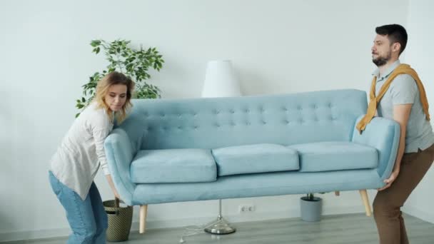 Νεαρό ζευγάρι φέρνοντας νέο καναπέ στο διαμέρισμα, στη συνέχεια, κάθεται χαλαρωτικό απολαμβάνοντας ανάπαυση κατά τη μετεγκατάσταση — Αρχείο Βίντεο