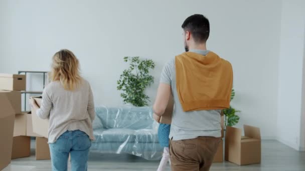 Slow motion van gelukkig gezin brengen dozen naar nieuw huis ontspannen op de bank knuffelen kussen — Stockvideo