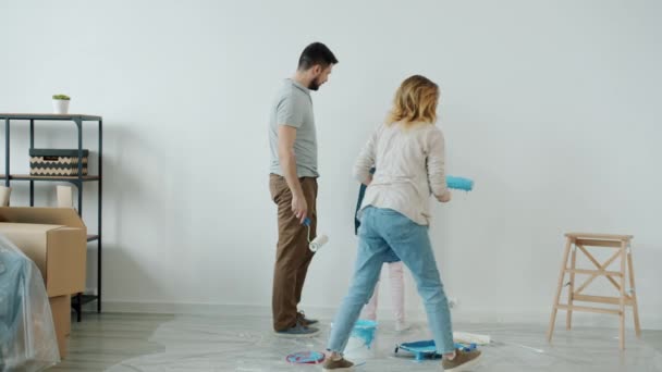 Slow motion of young family man woman and child painting house wall during relocation — Stock Video