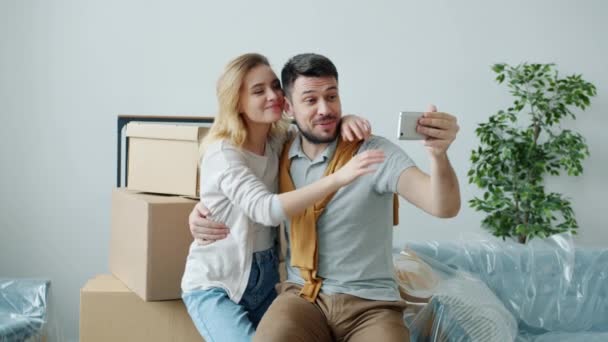 스마트폰으로 채팅하는 행복 한 커플들의 느린 움직임 박스가 있는 새 아파트를 보여 주는 스마트폰 비디오 전화 통화 — 비디오