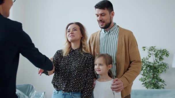 Slow motion of joyful couple with daughter buying house taking key from realtor hugging — Stock Video