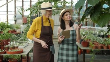 Serada yürüyen yaşlı ve genç kadınlar defterde yazarak konuşuyorlar.