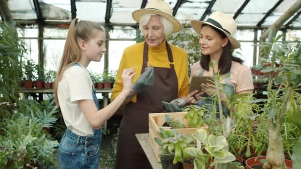 Slow motion of people farmers adults and kid talking looking at plants and writing in notebook in hothouse — Stock Video