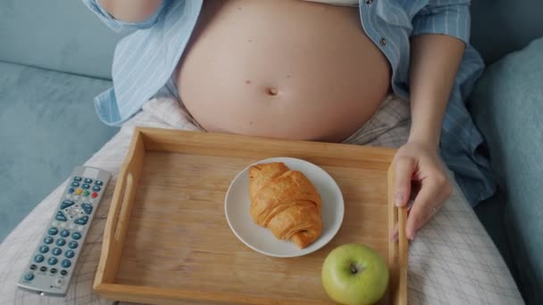 Gros plan sur les femmes enceintes ventre et mains profitant d'un repas sain et regardant la télévision à la maison — Video