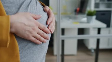 Hamile kadınların elleri karnını okşarken iş yerinde aşkı ifade ederken.