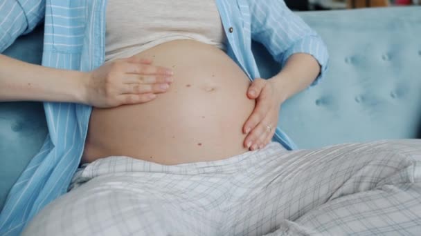 Primer plano de la mujer embarazada tocando la panza y luego haciendo forma de corazón con las manos — Vídeos de Stock