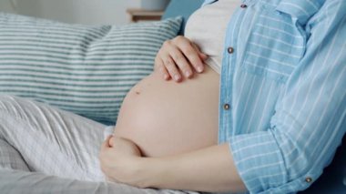 Güzel, genç bir bayanın eğilip karnını okşaması. Evdeki çocuğa sevgisini ifade etmesi.