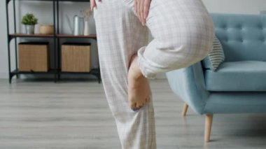 İyi görünümlü müstakbel annenin bir bacağının üzerinde dengede durması dairede yoga yapması.