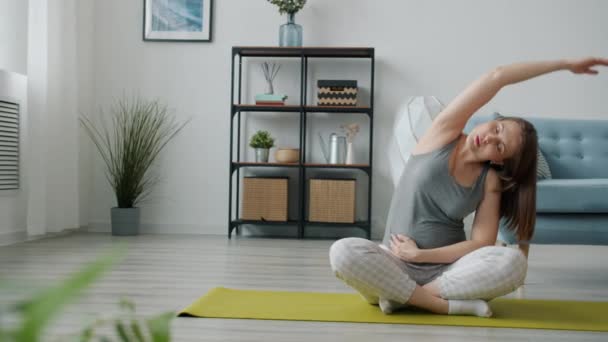 Senhora grávida ativa fazendo exercícios de alongamento, em seguida, relaxar na posição de lótus no tapete de ioga — Vídeo de Stock