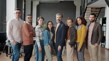 İş yerinde kameraya bakıp gülen çok ırklı bir grup insan.