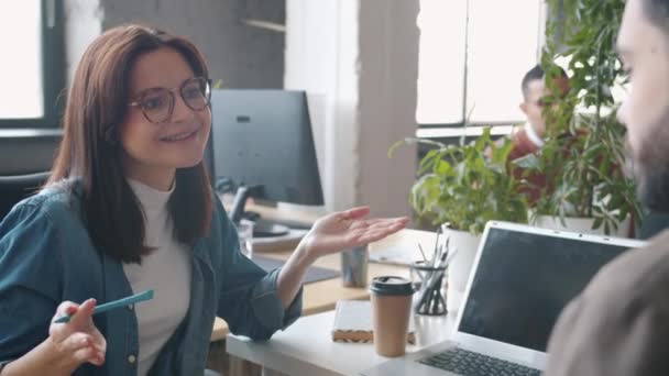 Giovane donna che parla con un collega maschio indicando lo schermo del computer portatile con il design dell'app per smartphone — Video Stock