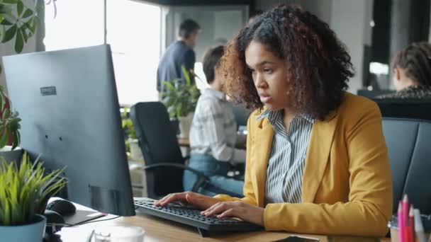 Zwolniony ruch Afroamerykanki wpisując komputer w biurze na otwartym planie — Wideo stockowe