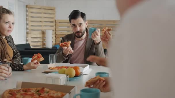 Gruppe af mennesker kolleger taler og griner nyder velsmagende pizza i kontoret – Stock-video