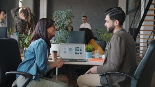 Projektanti aplikací Smartphone muž a žena mluví při pohledu na obrazovku notebooku v kanceláři — Stock video