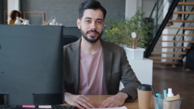 Orta Doğulu bir adamın portresi ortak çalışma yerindeki bilgisayar masasına gülümsüyor