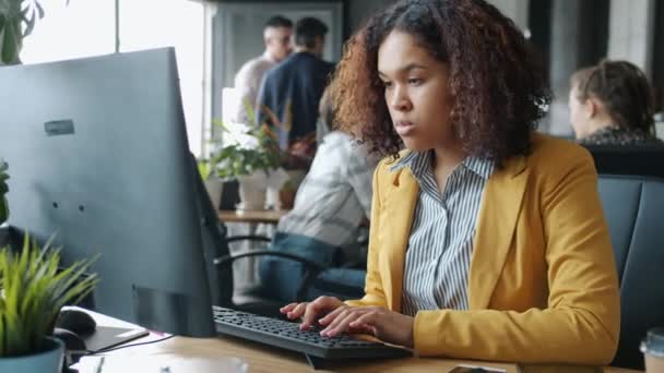 Aantrekkelijk Afro-Amerikaans meisje werkt met computer typen in co-working plaats — Stockvideo