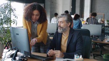 Meslektaşlar ve kadınlar ofiste bilgisayar ekranına bakarak iş konuşuyorlar.