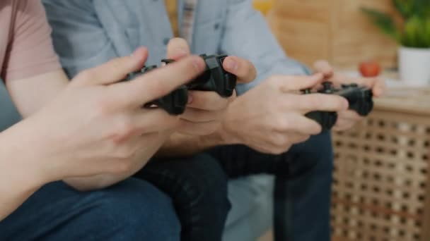 Крупним планом руки дитина і дорослий грають у відеоігри, використовуючи джойстики на дивані вдома — стокове відео