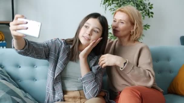 Teenager taking selfie with mom hugging woman making funny faces laughing at home — Stock Video