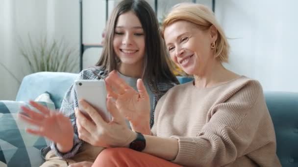 Genç kız ve olgun anne akıllı telefon ekranına bakarak evden video görüşmesi yapıyorlar. — Stok video