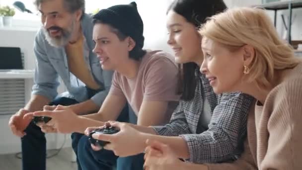 Joyful teenage girl winning video game playing with brother while parents watching and cheering — Stock Video