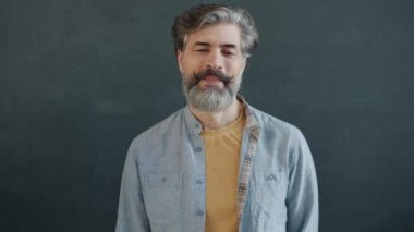 Neşeli, olgun bir adamın el hareketi yapan ve gülümseyen portresi.