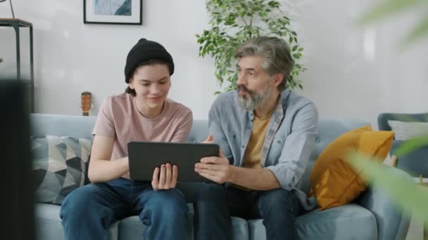 Pai e filho adolescente usando tablet conversando, em seguida, fazendo high-five passar o tempo de lazer em casa — Vídeo de Stock