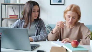 Anne ve kızı dizüstü bilgisayar kullanarak çevrimiçi eğitimle meşguller.
