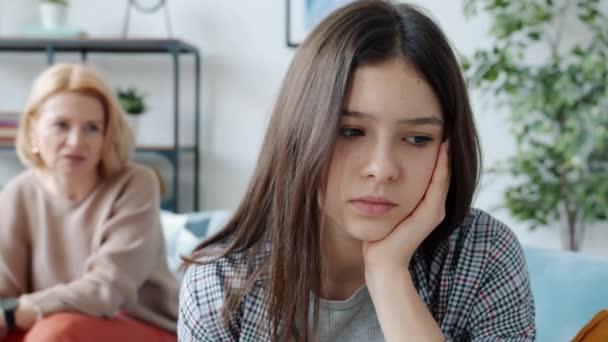 Slow motion portrait of sad teenage girl and mother yelling at her in background at home — Stock Video