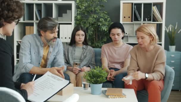 Boldogtalan család gyerekekkel, akik pszichológussal beszélgetnek, megosztják az érzéseiket az irodában. — Stock videók