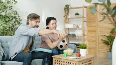 Aile babası ve oğlu TV 'de maç seyrediyor, top tutuyor ve beşlik çakıyor.