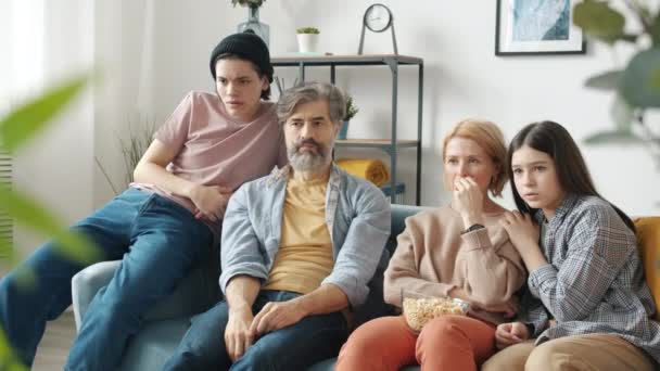 快乐的家人在电视上看恐怖片，表达恐惧，坐在沙发上聊天 — 图库视频影像
