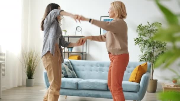 Zeitlupe von glücklicher Familienmutter und Teenager-Mädchen, die Händchen haltend tanzen und springen — Stockvideo