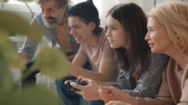 Çocukların video oyunu oynaması, rekabetin tadını çıkarması ve ailelere sarılması.