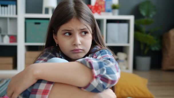 Portret nieszczęśliwej dziewczynki siedzącej na podłodze i rozglądającej się ze smutną twarzą — Wideo stockowe