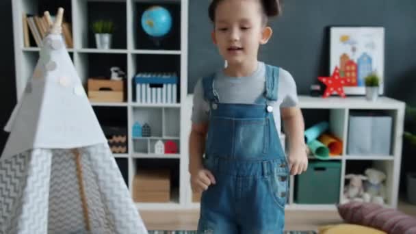Mooi kind dansen en zingen genieten van muziek binnen in appartement — Stockvideo