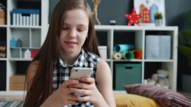 Akıllı telefon kullanan neşeli çocuk gülümsüyor dokunmatik ekran evde modern aletlerle eğleniyor.