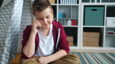 Neşeli çocuk cep telefonuyla konuşuyor ve gülümsüyor.