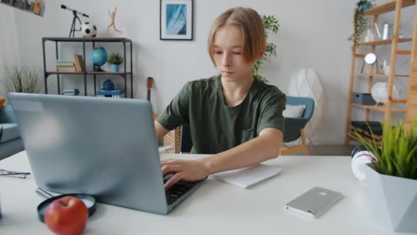 Смарт підліток друкує з ноутбуком, а потім пише інформацію в навчальному записі ноутбука вдома — стокове відео