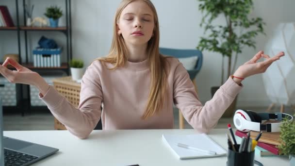 Adolescente faisant du yoga mains mobiles en namaste avec les yeux fermés relaxant assis à la table seul — Video