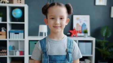 Evde durup kameraya gülümseyen masum küçük kızın yavaş çekimleri.