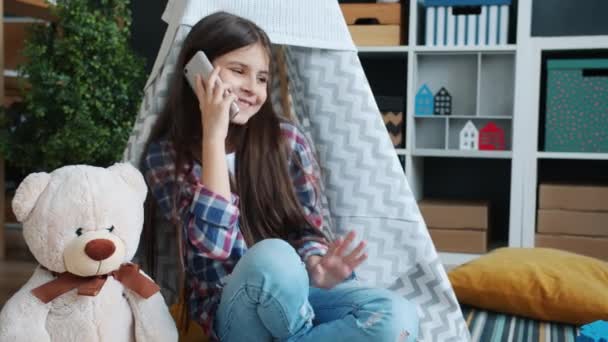 Glada barn chatta på mobiltelefon och leende diskuterar nyheter hemma — Stockvideo