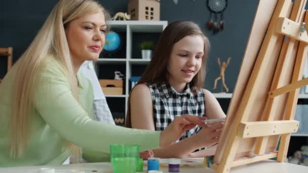 Dochter en moeder schilderen samen thuis werken met aquarellen en ezel lachend — Stockvideo