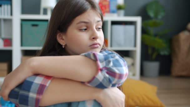 Portret van een kind dat op de vloer zit in de speelkamer en rondkijkt met een verveeld gezicht dat zich ongelukkig en gestrest voelt. — Stockvideo