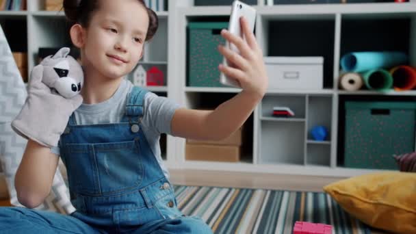 Powolny ruch szczęśliwego dziecka pozowanie do smartfona aparat gospodarstwa zabawka robi selfie sam w domu — Wideo stockowe