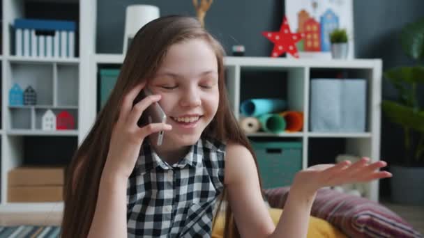 Criança feliz conversando no telefone celular rindo e gesticulando dentro de casa no quarto acolhedor — Vídeo de Stock