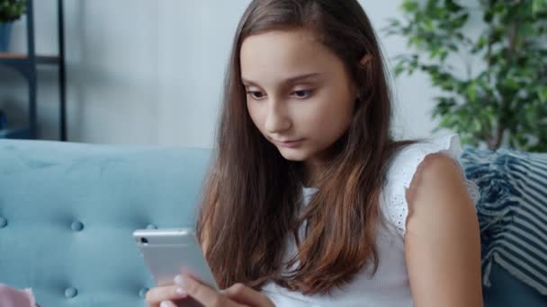 Современный подросток, использующий смартфон, получает хорошие новости, выражающие счастье дома — стоковое видео